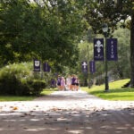 Group of students walking on an oak tree-lined walkway on the campus of Spring Hill College.